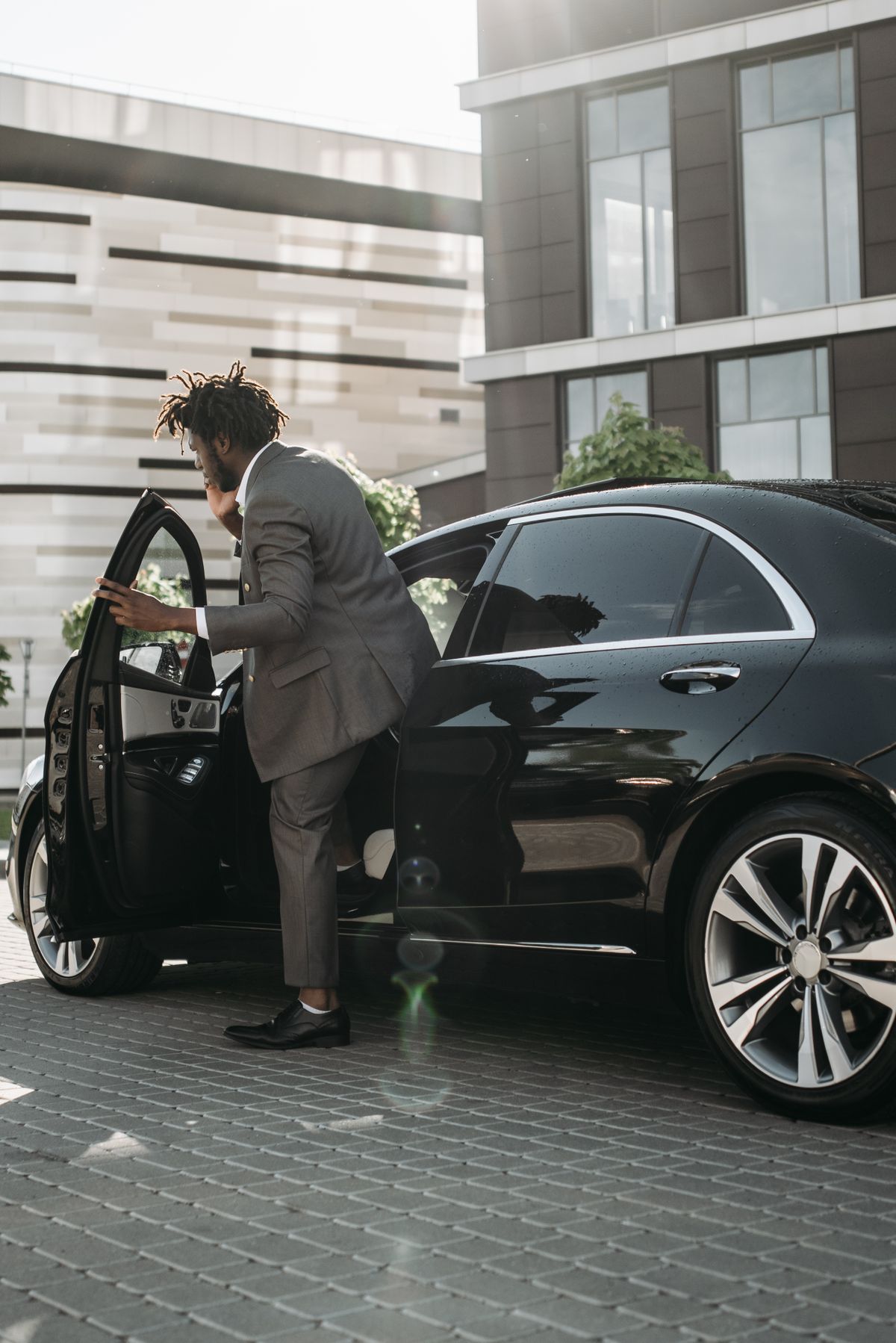 Passenger stepping into a chauffeured black luxury car